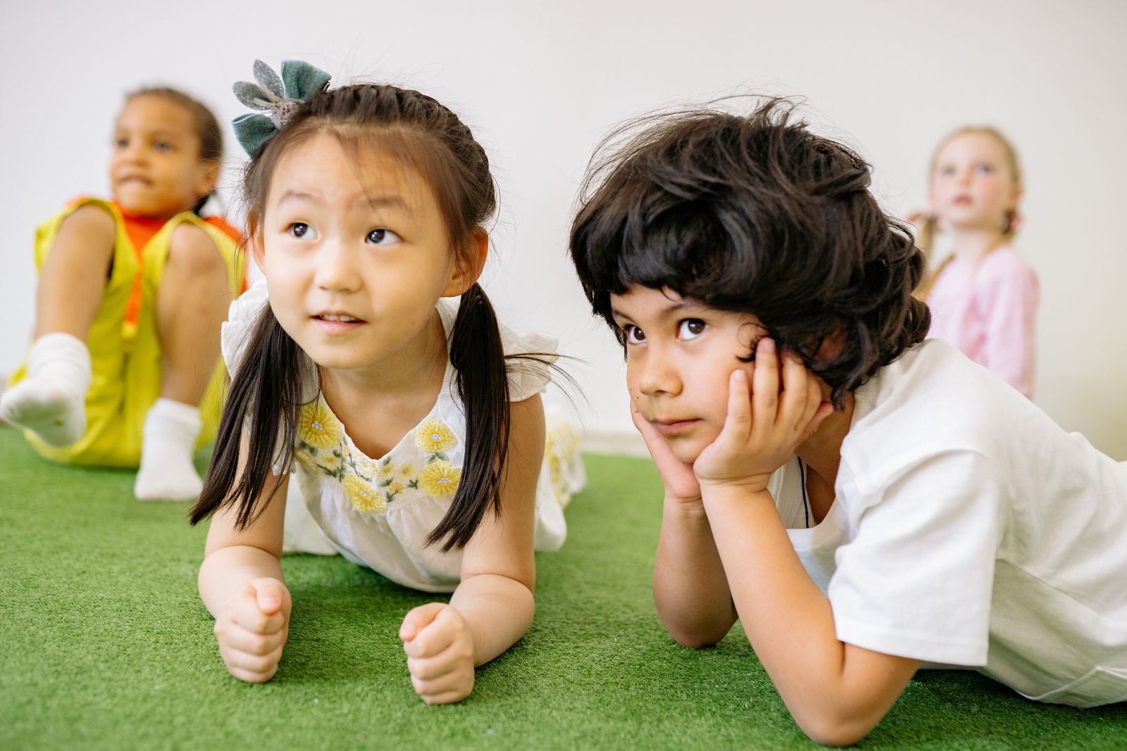 Two preschoolers lying on the grass carpet, smiling